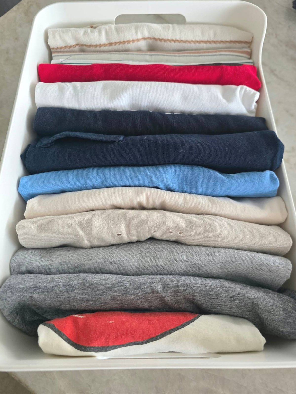 Drawer of t-shirts folded upright inside a tray